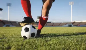Dos piernas sujetan un balón en un campo de fútbol