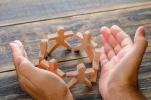 Dos manos rodean varias figuras que representan a personas dispuestas en círculo