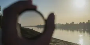 Persona sostiene una lente frente a un paisaje